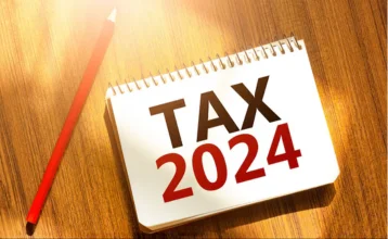 Tax 2024 written on a notepad, represents financial planning & record-keeping for the consecutive year